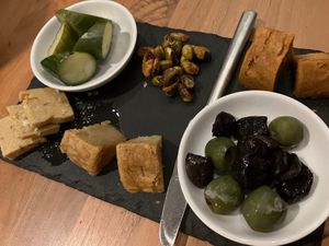 Artisanal cheese plate: pickled cucumbers, candied pistachios, aged cheddar, green and black olives, gruyere, and  smoked provolone at Althea in Chicago