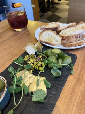 Cheese platter with dill pickles green olives, and roasted pistachios  at Althea in Chicago