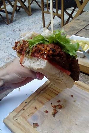 Foto de clienta comiendo dentro del establecimiento, al aire libre. Mitad del choripan vegano del menú. at Ubuntu Alimentos Sabios in Lomas De Zamora