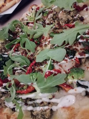 close up of the pesto chicken CBR pizza with aragula, garlic ranch dressing, broccoli at Virtuous Pie in Toronto