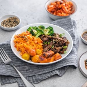 Kimchi Beef Bowl: Packed with immunity boosters: kimchi cous cous, ginger yams, roasted baby tomatoes, and roasted garlic broccoli topped with marinated bulgogi beef at Veggie Grill by Next Level - UCLA Ackerman Union in West Los Angeles