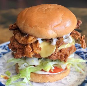 The Crunchy Wylde Chkn Sandwich served on a buttered brioche bun, crispy homemade fried onions, chkn patty, cheese, house-made Ranch dressing, lettuce and tomatoes. at Hang Space in Richmond