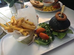 The cheeseburger with charcoal bun, onion rings and fries.  at Naked Bakery in Edinburgh