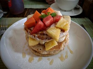 Stack of vegan pancakes with mixed fruit and maple syrup at Ganita Cafe in Pai