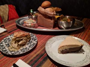 Clockwise from bottom left: Brown Butter Rosemary Apple pie, daikon slaw, BBQ jackfruit, rolls, yucca chips, jicama slaw, ancho chicken, and Whiskey Chocolate Cream pie. at Rood Food and Pie in Lakewood