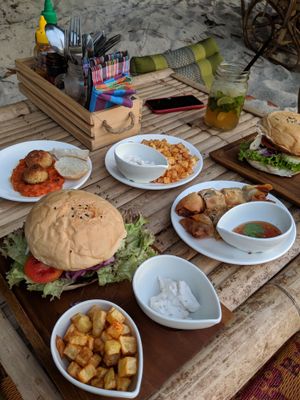 A nice spread, eaten casually on the beach: burgers, not-meatballs, spring rolls, potatoes with vegan aioli, delicious Thaijito cocktail at Benny's On The Beach in Koh Lipe