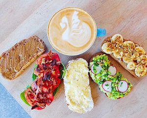 Latte; Toast options (left to right) on vegan sourdough bread: granola butter toast; super avocado toast; banana bread toast at Revolucion Coffee & Juice in San Antonio