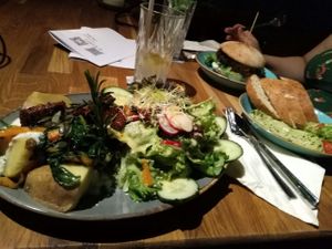 Fully loaded baked potato, avocado cream on the side, burger in the back. at Mokel Bar in Muenster