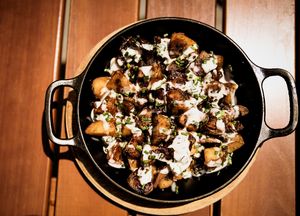 Pan fried potatoes ( Bratkartoffeln ) in iron skillet , tempeh bacon, balsamic vinegar reduction, creamy vegan herb yogurt sauce  at Hinterhof in Los Angeles