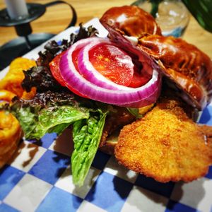 Schnitzel Sandwich-  house-made seitan cutlet, breaded and fried golden brown, lettuce, tomato, onion, mayo, on a pretzel knot roll. Served with curly fries!  at Hinterhof in Los Angeles