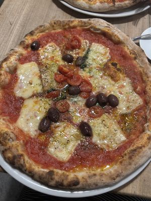 Marinara pizza topped with tomato sauce, cherry tomatoes, basil, taggiasche olives, garlic, oregano, and vegan mozzarella  at Simbiosi in Florence