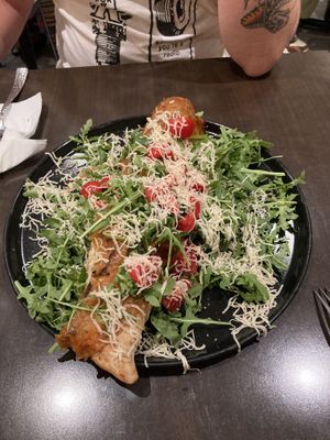 baguette shaped crust filled with ricotta and mozza, speck ham on top, sprinkled with parmesan - with salad and tomatoes  at Utopia in Nice