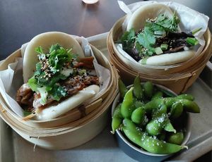Vegan bao bun-pack. One with tofu, the other with portabello mushroom. Edame beans in small bowl. at Magnolia in Stockholm