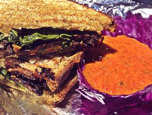 TLT Panini — Soy free maple tempeh, creamy vegan cheesy pesto on wheat French bread, lettuce, tomatoes, and herby roasted red-pepper, garlic, basil, coconut cream sauce for dippi at Daily Fuel in Portland