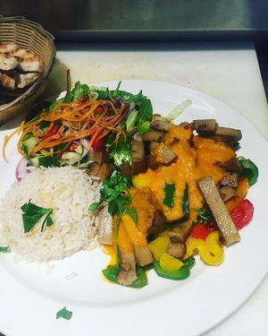Seitan cooked with mix vegetables in rich spicy tomato sauce and serving with rice and mix salad  at De Mezka in North London