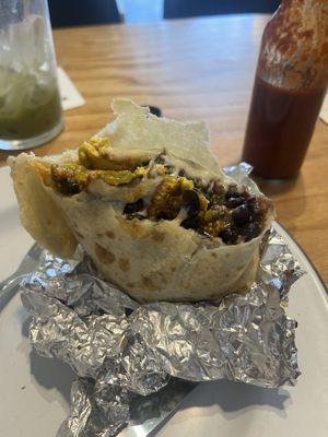 Beso del Chorizo burrito is packed with tofu scramble, potatoes, green chile, vegan cheese, jackfruit chorizo, beans, and finished with a rich cashew crema, onions, cilantro, and a at Hoja in Denver