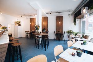 Light interior with a lot of white, wood, marble, many plants and a beautiful blue floor  at Camion in Antwerpen