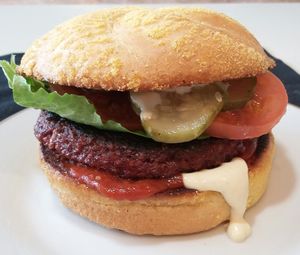 Full Taste burger (brown rice, roasted beets, onions, roasted peppers, herbs, spices) on a cornmeal roll with house made pickles, house ketchup, Dijon, lettuce, tomato. at A Full Taste in Decatur