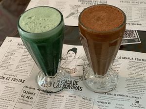 Fresh juice with aloes, ginger, orange, celery and spirulina Smoothie with cacao, bananas, strawberries, jackfruit, maca powder and almond milk at La Casa de las Mayoras in Cancun
