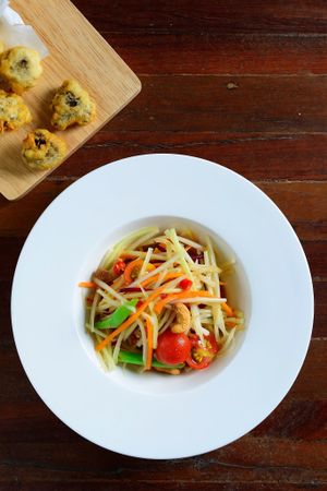 Spicy Green Papaya Salad with Fried Seasoned Mushroom Stipe. at Tonklar Facai - Chula in Bangkok