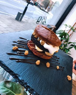 A dessert burger! A black pea brownie, coconut yoghurt, banana and a mint leaf between focaccia buns drizzled with date syrup and mulberries.  at Plant Club in North London