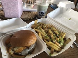 “Dirty Hot” BRIOCHE BUN, MOVING MOUNTAINS PATTY, VEGAN MOZZARELLA, TATER TOTS, SWEET CHILLI, SRIRACHA MAYO, JALAPENOS with fries in garlic butter, garlic mayo and spring onions at Kibae (Formerly Plant Hustler) in Poole