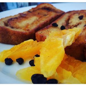 Vegan cinnamon swirl French toast with black currants and orange slices  at Hugo's - West Hollywood in West Hollywood