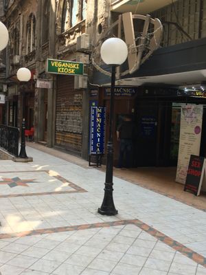 When you pass through the archway, you will see this interior square with streetlights and a green and yellow sign. The kiosk is in an archway beside the sign. at Veganski Kiosk in Belgrade