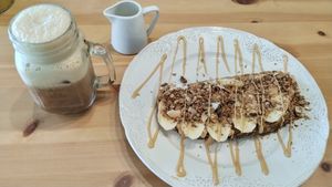 Banana toast with granola and peanut butter with an iced coffee on the side. at Bali Food & Drinks in Leiria