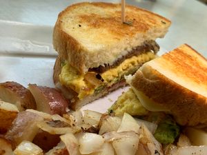 Breakfast Sandwich: Vegan Eggs, Vegan Sausage, Vegan Cheeze topped with Tomatoes, Avocado on English Muffin Toast, served w/ choice of Potatoes at Anna's House in Kalamazoo