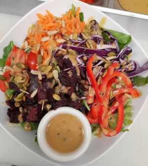 Rainbow garden salad with Plantitude's signature miso dressing. It includes Tuscan greens, carrots, purple cabbage, red peppers, roasted beets, toasted seeds. at Plantitude in Ladysmith