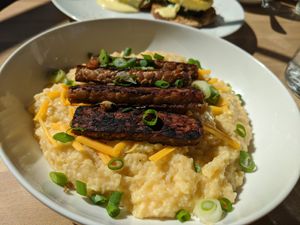 Creamy cheesey grits topped with scallions, crispy tempeh bakun at Verdine in Houston