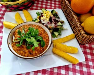 Homemade and gluten free lentil bolognese, topped with rocket , salad side and crispy organic polenta fingers at Catchacarrot Vegan in Ardfern