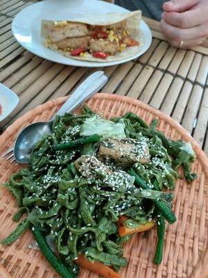 Spinach noodles in pesto sauce (vegan) with smokey tempeh and tofu tortilla in the background at Mama's Garden - Maybe closed in 