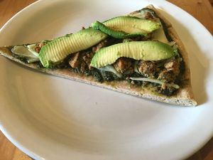 Custom slice with pesto soy cheese tofu-ricotta and fresh avocado on top at Slice of Life in Sebastopol