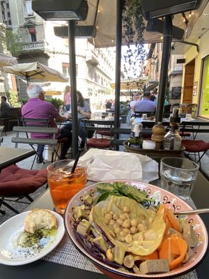 Vegan salad with added smoked tofu, bread and olive on the side and an aperol spritz  at Bruscè in Bologna