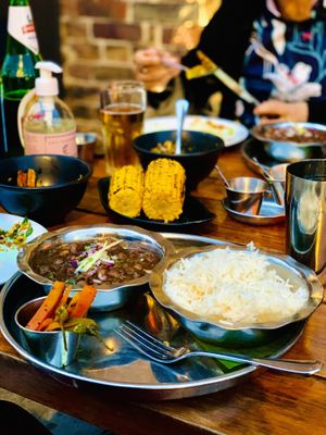 Chloe Chawal plate (vegan + GF) next to sides inc grilled corn on the cob, okra chips and Bhel   at Dishoom - King's Cross in London