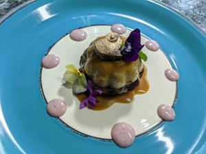 The 'impossible' cake. Chocolate base, cheesecake-like cream and caramel sauce topped with a mint and edible gold chocolate and surrounded by strawberry cream dots. at The Culinary Alchemists in Nuevo Arenal