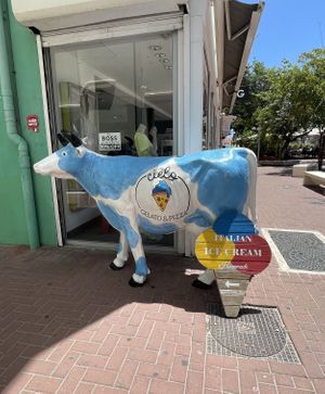 Sky cow sign pointing down the alleyway  at Cielo Gelato & Pizza in Willemstad