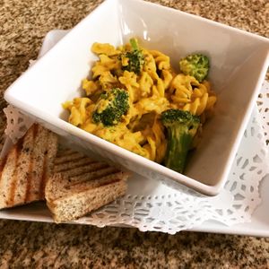 Mac 'n Cheese made with Quinoa Pasta, faux Sausage Queso, and fresh broccoli served with a slice of 10-Grain Bread at Rawfully Yours Juice Bar & Cafe in Lasalle