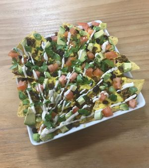 Loaded Nachos! Organic Chips, (Cashew) Queso, Plant-based Chorizo, Diced Organic Tomatoes, Black Beans, Green Scallions, Fresh Avocado, Drizzled Cashew Sour Cream, & Cilantro at Rawfully Yours Juice Bar & Cafe in Lasalle