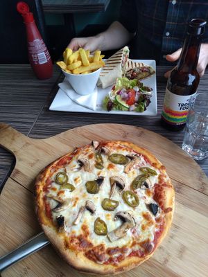 Vegetarian pizza in foreground and vegan falafel wrap in background at Captain's Table in Findhorn
