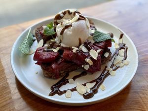 Vegan french toast with vanilla roasted rhubarb and coconut ice cream, garnished with almonds, mint, and carob syrup. at Little Lotus Cafe in Hobart