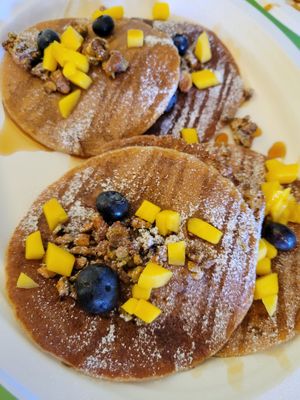 2 orders of the blueberry and mango pancakes garnished with pistachio brittle at Hijo De Su Madre in Los Angeles
