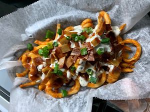 Loaded Fries - Seasoned curly fries topped with cheese sauce, bacun, ranch, and green onions. at Seitan's Realm in Columbus