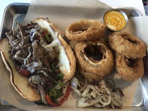 Philly Cheesesteak with onion rings  at The Modern Vegan in San Diego