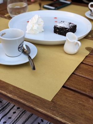 A chocolate brownie with cream (all vegan) with espresso and rice milk (as recommended by staff instead of soy milk, which negatively impacts the flavour of the coffee).  at Cavo Bistrot in Cagliari