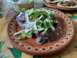 Several tortillas smothered in a black bean sauce at Aguacate Limon in Tulum