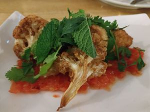 Fried cauliflowers over tomatoes and green tahini. at Kukla in Valencia