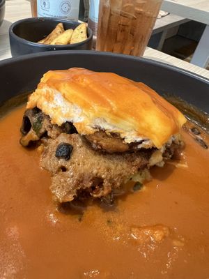Showing the hearty filling of the Francesinha style Portuguese Sandwich (vegan). Shredded seitan, Beyond Meat Sausage, mushrooms, tomato in bread covered in Francesinha toppings.  at Kind Kitchen in Porto